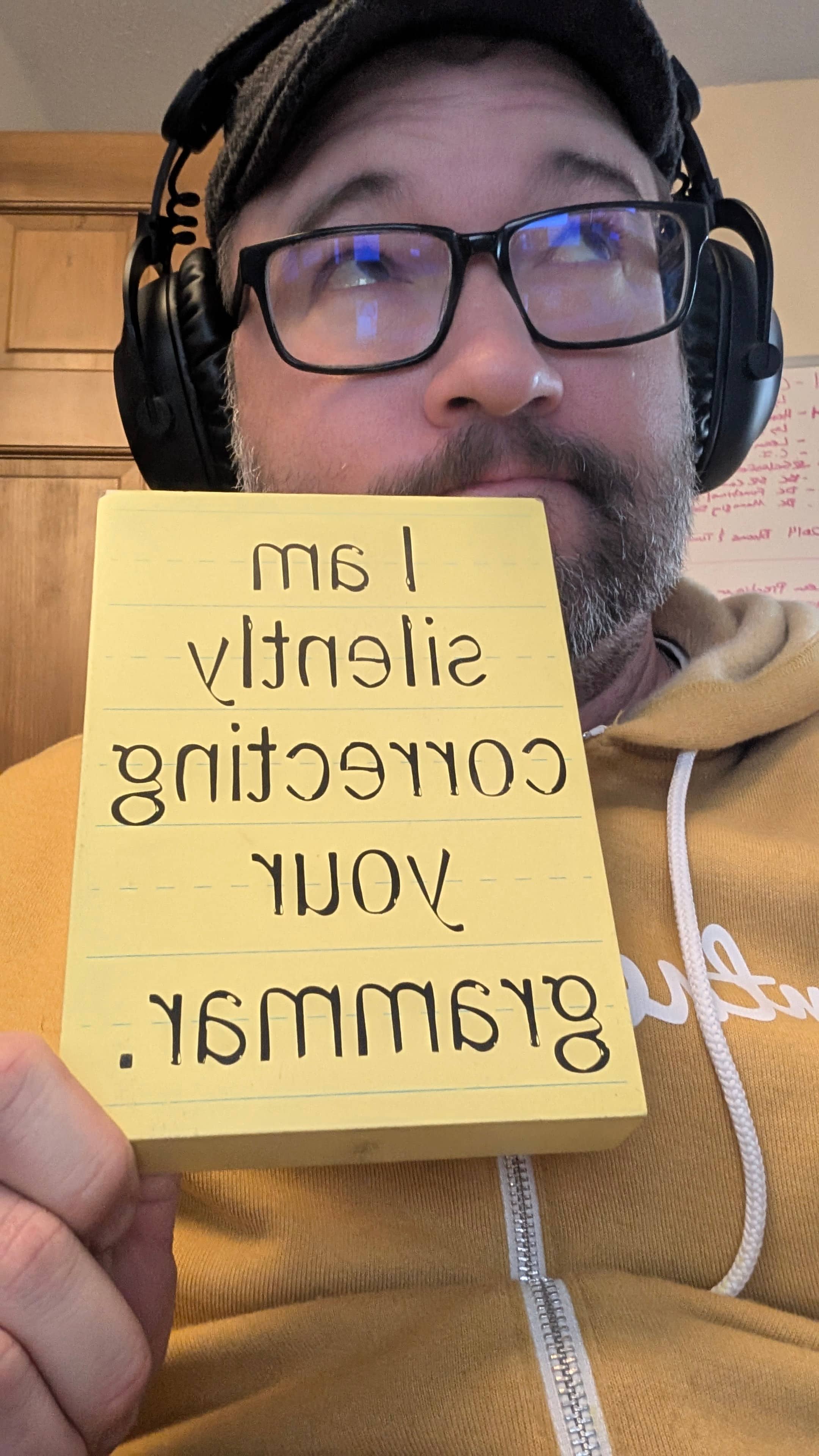 Holding a sign: I am silently correcting your grammar